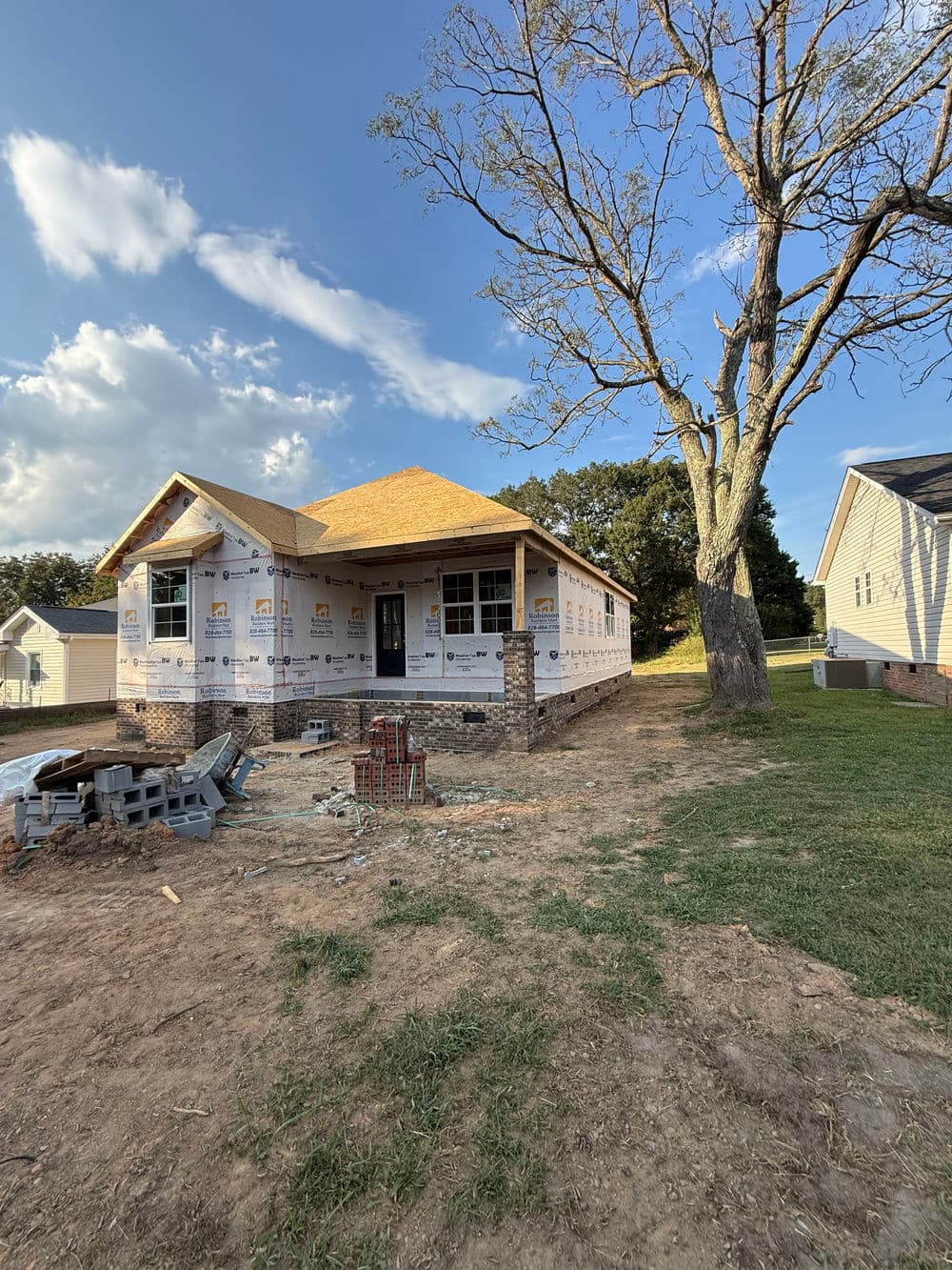 Newly constructed house with partial brick facade and exposed natural surroundings.