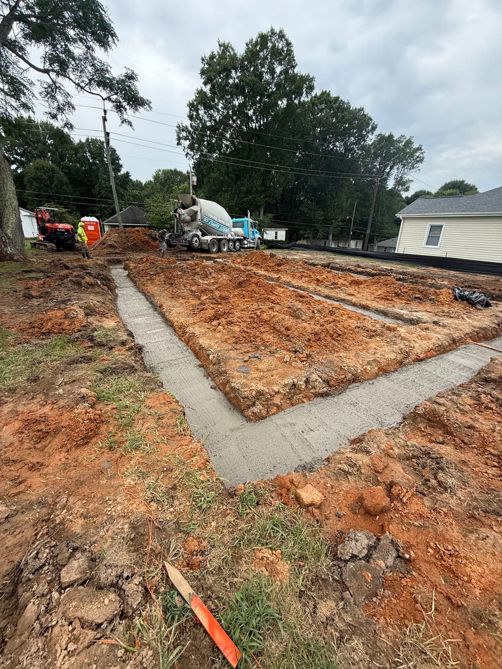 Concrete foundation being poured at a construction site with machinery and equipment.