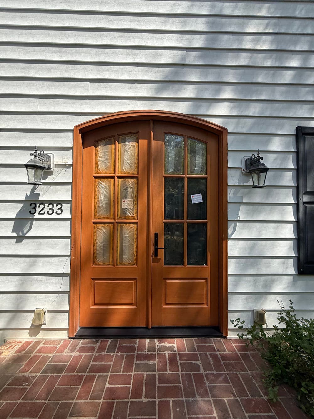 Front view of a charming wooden double door with glass panels at a residential home.