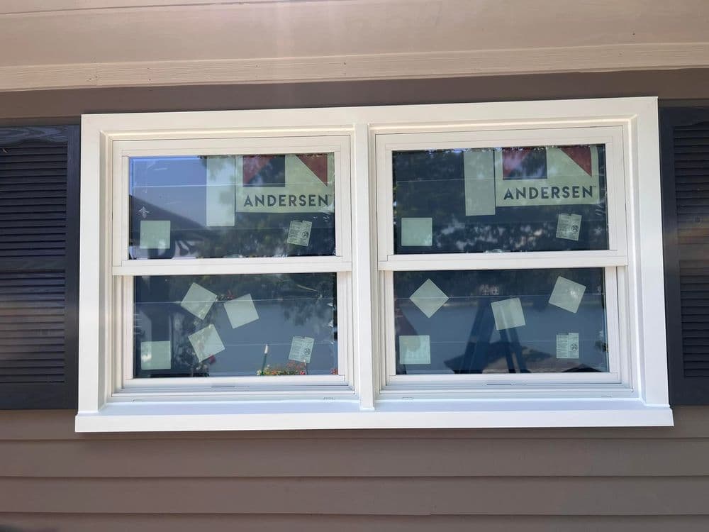 Andersen windows with information labels on a house exterior, showcasing modern design.