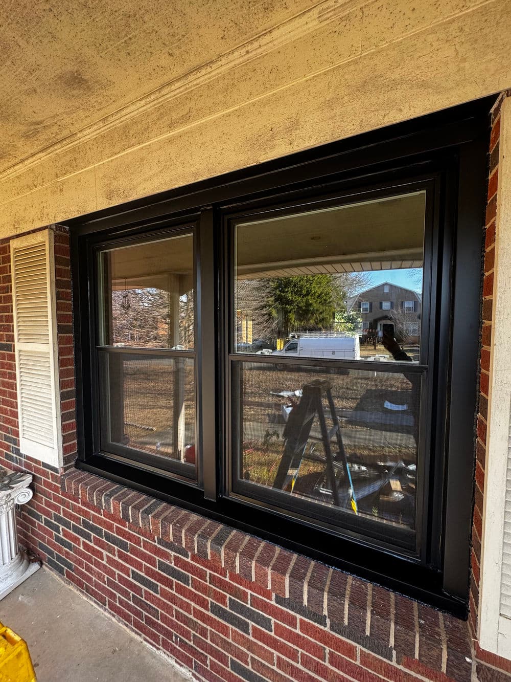 Black-frame windows installed on a brick exterior, showcasing a clear view of the outdoors.