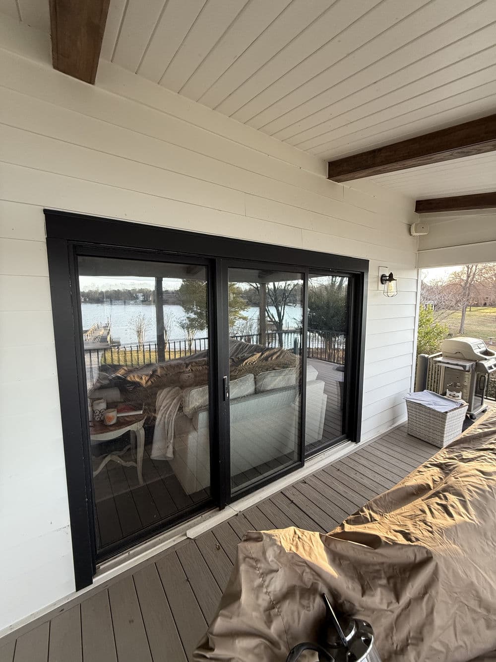 Sliding glass doors open to a scenic lake view from a cozy outdoor patio.