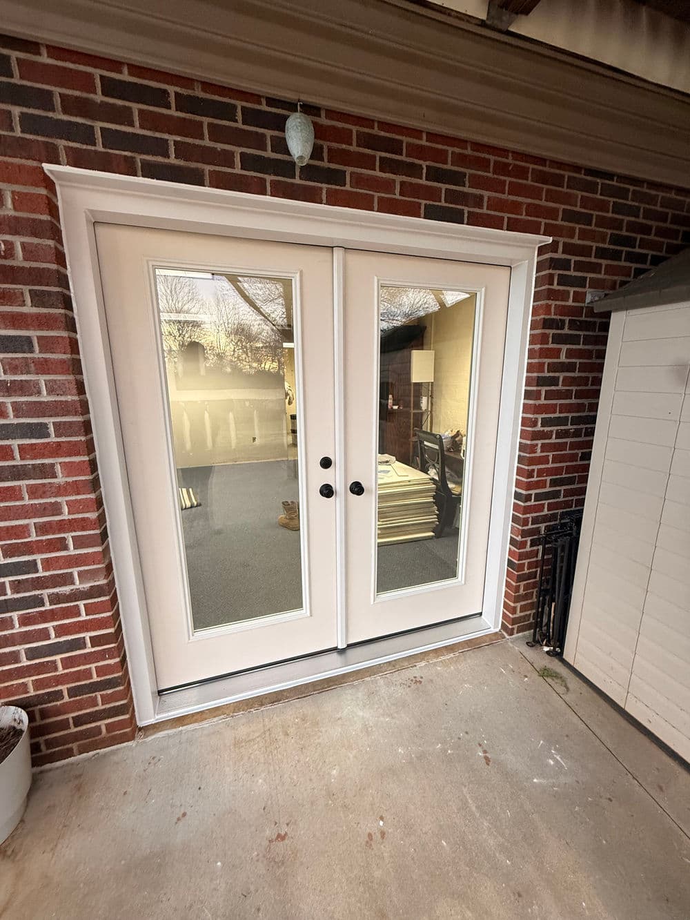 White double doors with glass panels, framed by a red brick wall, leading to a patio area.